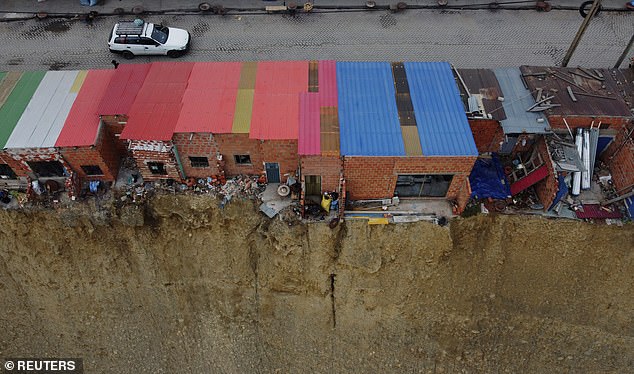 The image shows a thin row of flimsy structures hanging from the edge of the cliff.