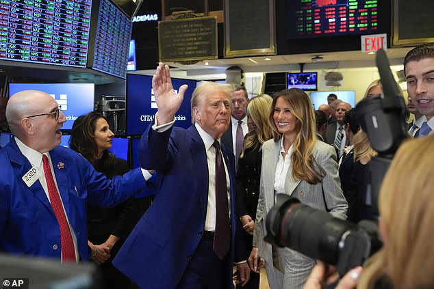 Donald Trump waves with Melania as he walks across the show floor