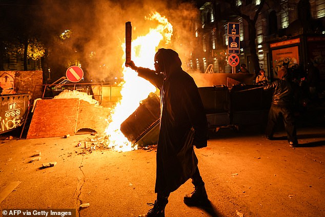 Protesters light a fire at the base of a makeshift barricade erected on a Tbilisi street during demonstrations against the government's decision to delay European Union membership talks amid a post-election crisis, early December 1, 2024.