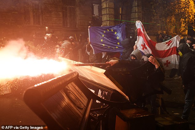 Protesters carrying Georgian and European flags clash with police during a demonstration against the government's decision to delay European Union membership talks amid a post-election crisis, in Tbilisi, early on December 1, 2024.