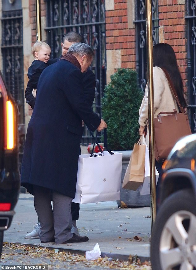 Baby Holland seemed to be in a delightful mood as her grandfather carried a bag full of presents