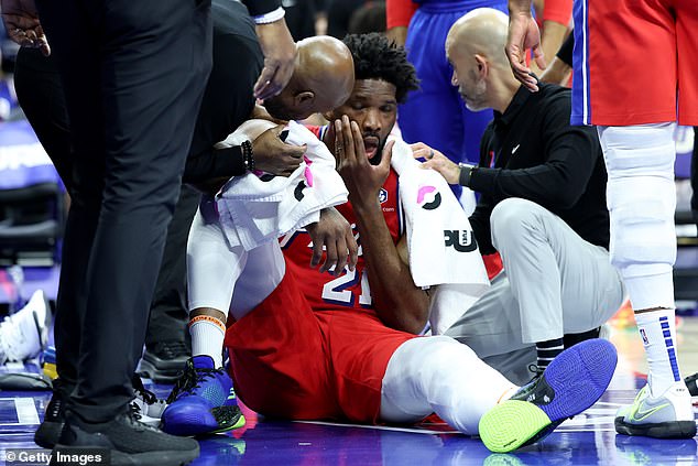 Embiid is treated by medical personnel before leaving the arena for further medical evaluation.