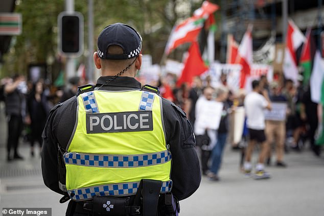 Commander Read said 13 people are being investigated for allegedly displaying symbols of illegal terrorist organizations (pictured, a police officer at a pro-Palestinian rally in Perth).