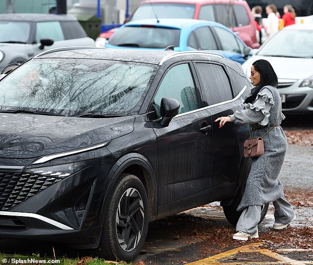 To keep warm in the rainy weather, Katie opted for a gray winter coat with ruffled sleeves and gray sweatpants and sneakers.