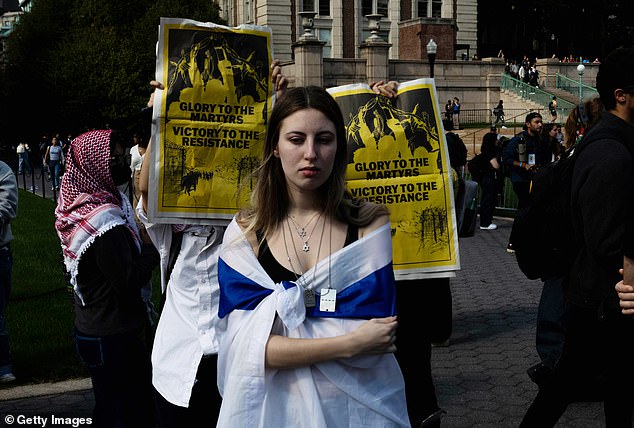 The demonstrators surrounded two Jewish students who were holding a vigil while carrying an Israeli flag over their shoulders