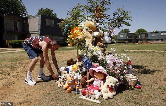 Johnny Tunstall (L) places a bear at a memorial outside the apartment complex where the crime occurred in Purcell, Oklahoma on Monday, April 17, 2006, after the hearing for Underwood