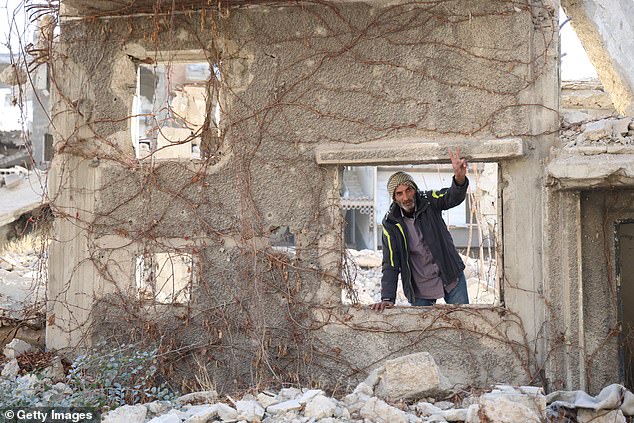 A man peers out of the window frame of a ruined building on December 14 in Jobar, Syria.