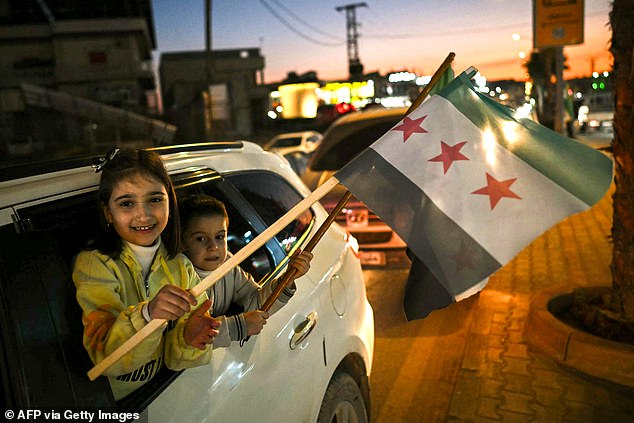 Children wave a Syrian independence-era flag in the town of al-Dana, near Sarmada, in northern Syria's Idlib province, on December 13.