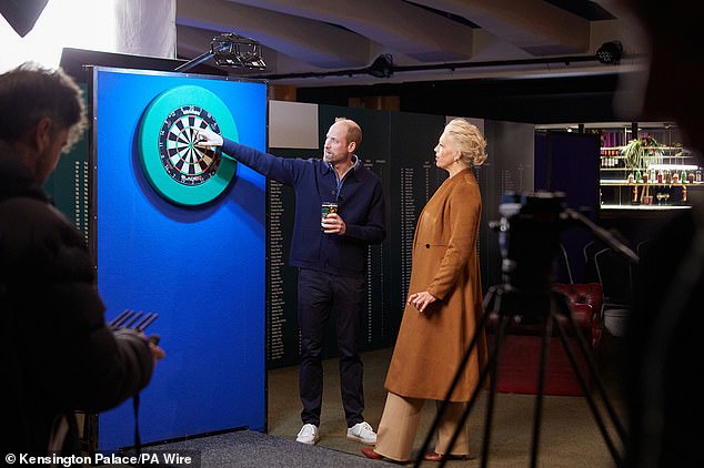 Dressed in plastic-free trainers from British brand HEVEA and a casual blue jumper, the Prince looked relaxed as he threw darts with Waddingham, 50, and drank a pint of cider in the bar.