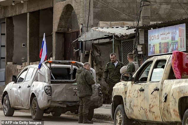 Russian soldiers wait next to military trucks as they prepare to evacuate a position in Qamishli, northeastern Syria.