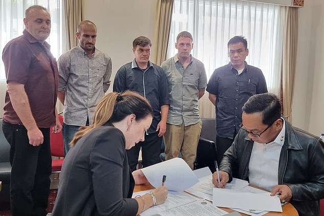 Martin Stephens, Michael Czugaj, Scott Rush, Matthew Norman and Si Yi Chen watch as Australian and Indonesian officials sign their releases before returning to Australia on Sunday.