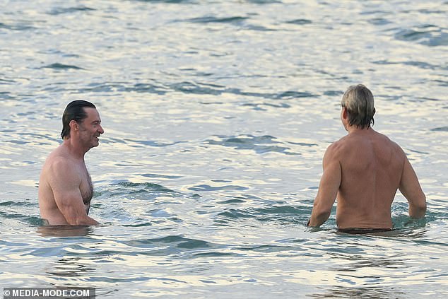 Hugh was seen laughing as he chatted with his friend while relaxing in the ocean.