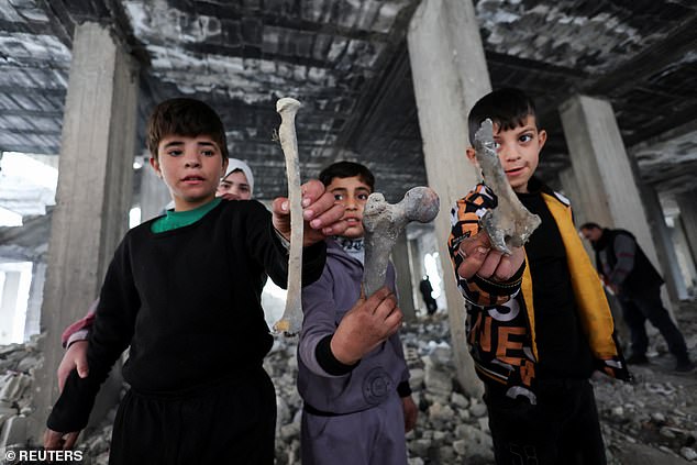 Children hold bones of different shapes found in the Tadamon district, filled with remains of what residents and human rights groups described as years of killings there under Bashar al-Assad's rule in Syria.