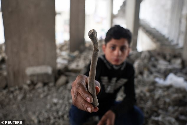 A Syrian boy holds a human bone while playing in the Tadamon district