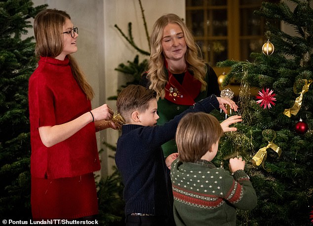 Princess Estelle, Prince Oscar and Prince Gabriel hang their Christmas decorations on one of the trees at the Royal Palace