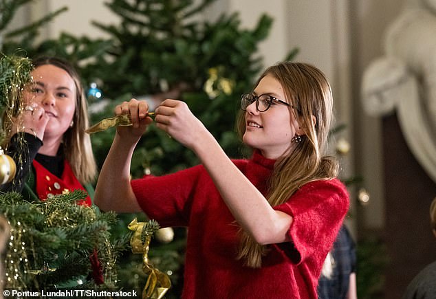 Princess Estelle pictured deciding where to place her Christmas tree ornament