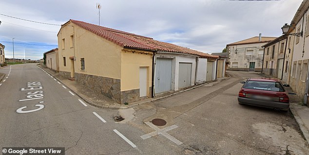 The person, who can only be seen from afar and is not visible in closer shots of the road, is located around the corner where the red car was parked.