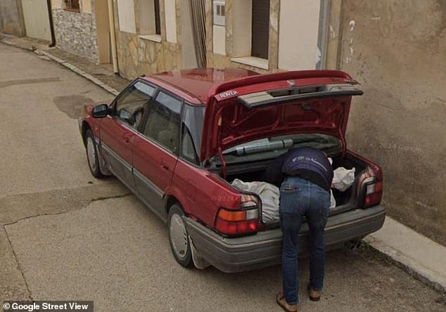 The photo shows a man carrying what appears to be a body bag into the trunk of a red car, local media report.