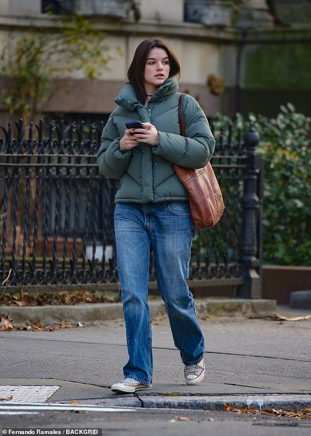 The nepo baby wore relaxed straight jeans with gray sneakers while carrying a studded brown leather tote bag.