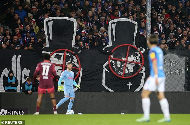 Klopp appears in the spotlight next to a tombstone on a banner at a Bundesliga match.