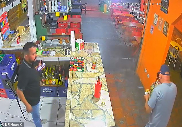 Shop owner Christian de Souza Amaral, who witnesses the sandwich erupt, gapes in shock as the stunned customer attempts to wipe the burning filling from his face.