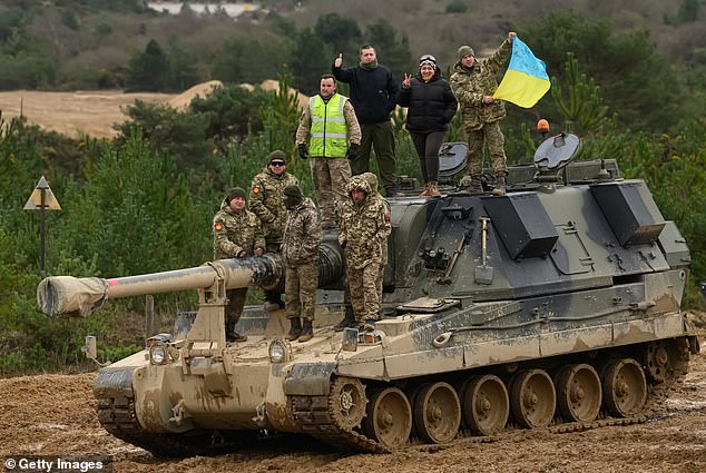 Ukrainian recruits and their trainers from the British Armed Forces pose for a photograph on an AS90 self-propelled artillery system at a military installation, February 23, 2023 in southern England.