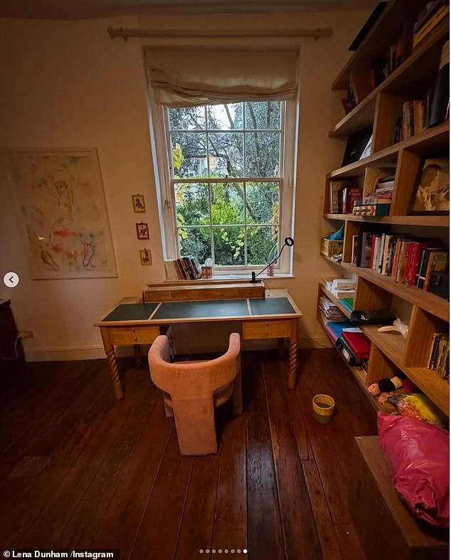 The office space features a sleek wooden floor, a quirky pink fabric seat, and garden views.