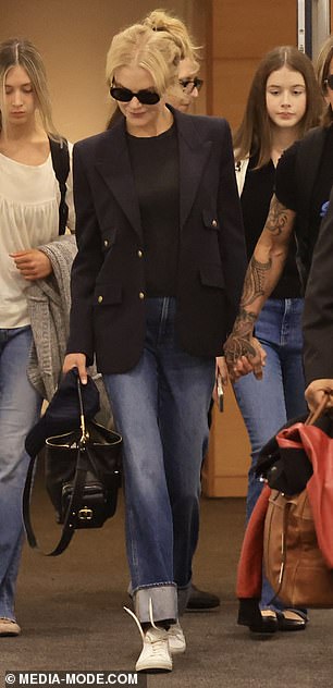 For his travels, he cut a stylish figure in a black T-shirt and straight-leg denim jeans.