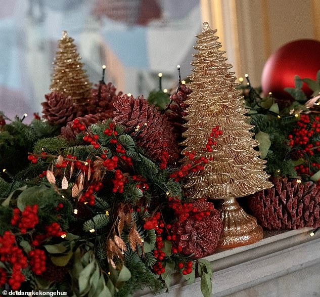 The mantelpiece of the royal residence is decorated with a garland adorned with red berries.