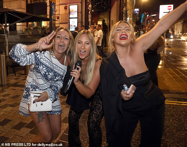 LEEDS: A blonde woman grabs her karaoke microphone on the street as two friends sing