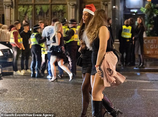 CARDIFF: Two women, one wearing a Santa hat, stroll down the street, oblivious to the chaos behind them.