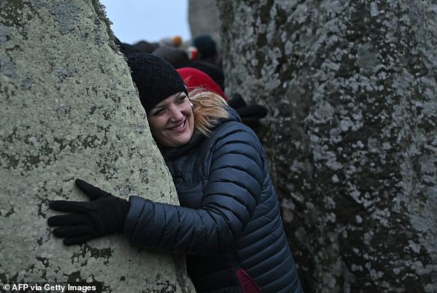 A reveler interacts with a stone as people gather to celebrate the pagan 'Winter Solstice' festival at Stonehenge.