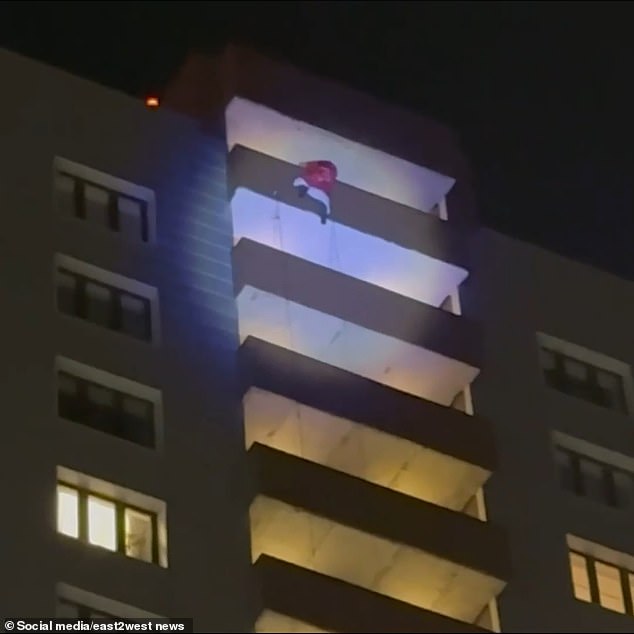 Grandfather Frost is seen in his red fur coat trying to descend the building