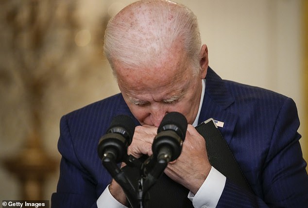 US President Joe Biden pauses and grabs his folder as he listens to a question from a reporter.