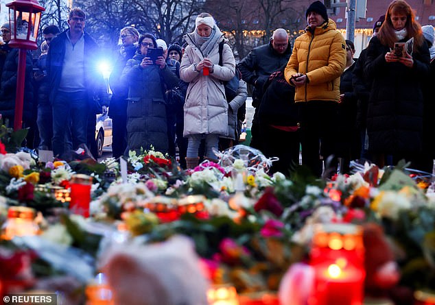 People stand next to candles and tributes near the site where a car plowed into a crowd at a Christmas market in Magdeburg