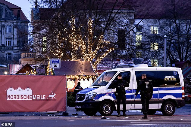 German police officers stand guard next to their vehicle at the scene of a vehicle attack on the Christmas market in Magdeburg, Germany, on December 21, 2024. According to Magdeburg police, at least two people were confirmed dead, Dozens were injured and the suspect, a Saudi citizen, was detained.