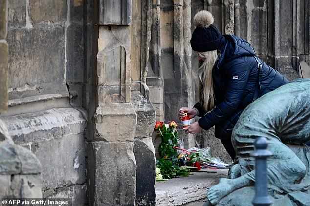 A mourner lights a candle today near the Christmas market, where a car crashed into a crowd killing at least two and injuring more than 60 people the night before. At least two people died and more than 60 were injured