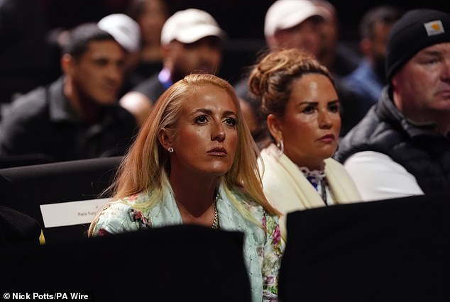 Paris looked typically elegant in a long blue coat adorned with flowers as she sat in the crowd and watched the warm-up fights.