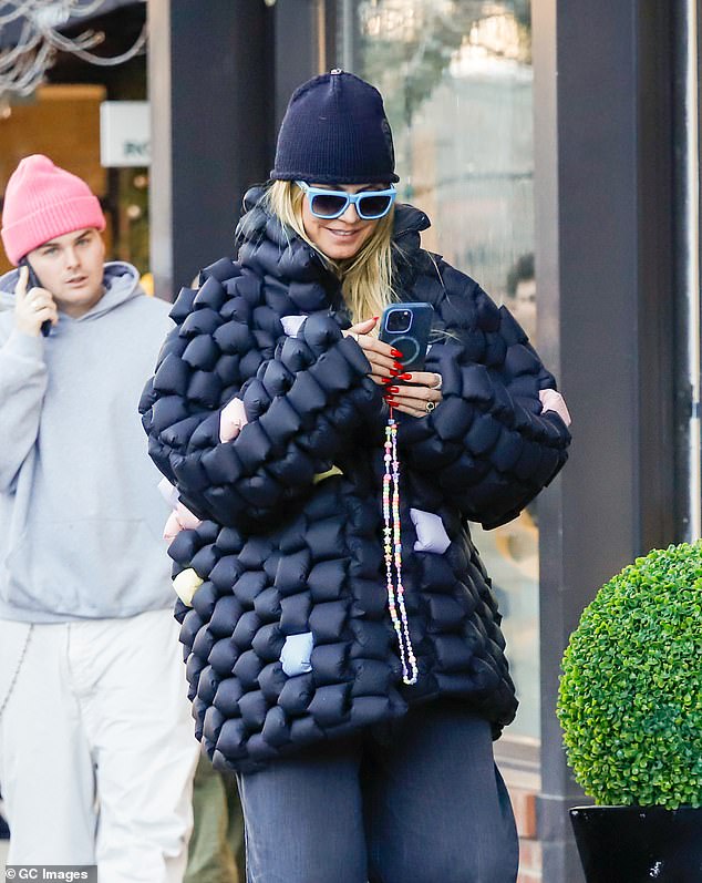 The blonde beauty added a black beanie and a pair of blue-framed sunglasses to her casual look.