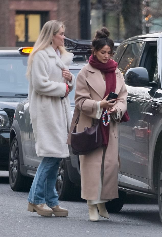 While out and about, Michelle (right) kept warm in a long beige coat which she paired with a dark red scarf and a white knit dress, while Nicoline (left) wore a fluffy white jacket.