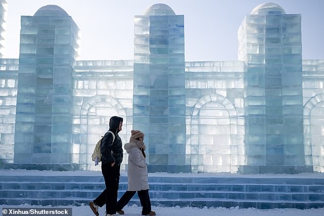 Two tourists standing next to the wall of a building show the scale of the monuments.