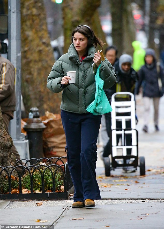 She was wearing a pair of headphones while out and about and carrying a green shopping bag.