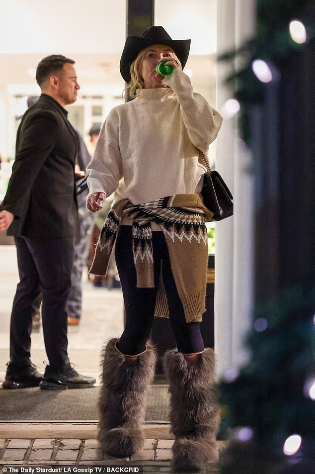 She was photographed drinking from a green bottle during her outing and wrapping another sweater around her waist.