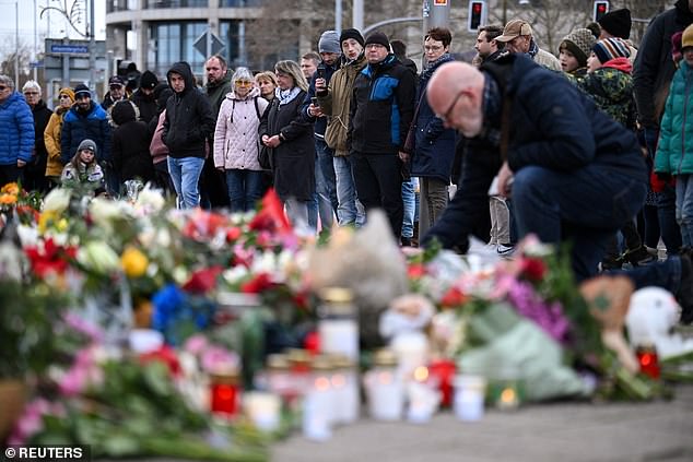 People leave candles and floral tributes at the Alter Markt in Magdeburg, where a man drove a car into the crowd on Friday evening