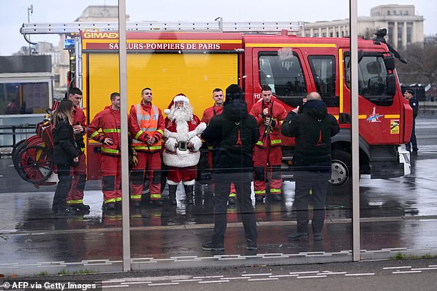 Firefighters pose for a photo with a Santa Claus near the Eiffel Tower as the site was closed and then reopened after a fire was reported in Paris, December 24.