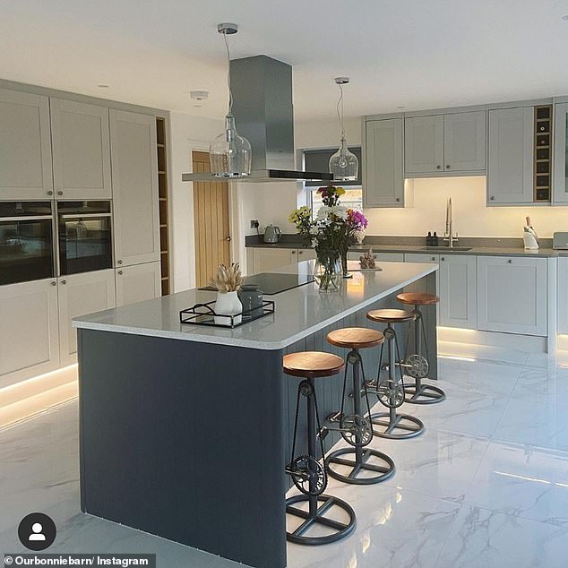 At the center of their home is a wide open space with a large white kitchen complete with a white marble island, bike-themed stools, and countertops that feed into a living room.