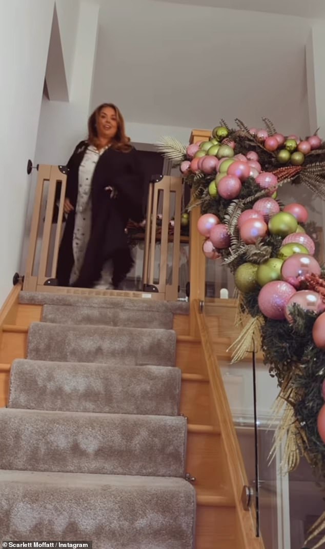 Scarlett's decorations extended to her large home, with a bauble and holly garland winding up the glass stairs to the balcony landing that overlooks her open-plan living space.