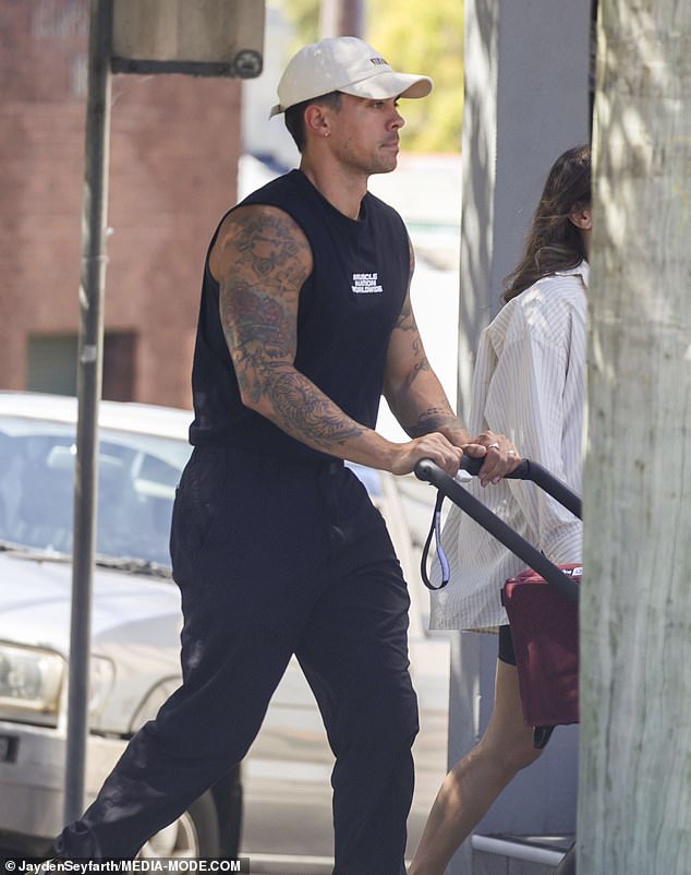 He completed his monochrome look with Adidas sneakers and a white baseball cap and looked excited to embrace fatherhood as he pushed his son's stroller down the picturesque Sydney street.