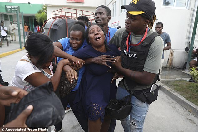 The wife of a journalist shot during an armed gang attack cries as an ambulance carrying his body arrives at another hospital in Port-au-Prince, Haiti