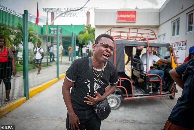 A journalist cries outside La Paixe Hospital in Port-au-Prince, Haiti